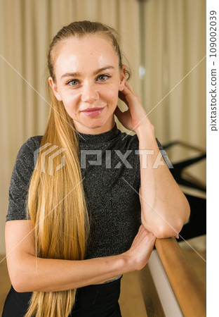 Portrait Female ballet dancer resting at barre and mirror in dance studio - dance and ballerina concept 109002039