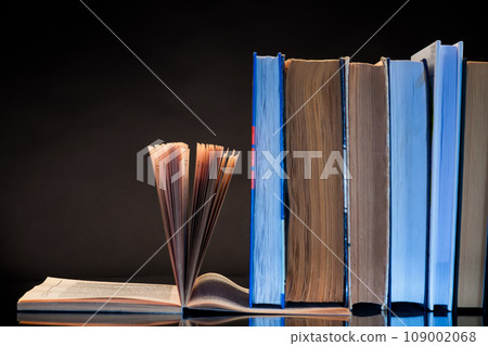 open book for reading and a stack of books open book for reading and a stack of books 109002068
