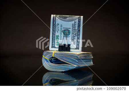stack of dollar bills collected in an elastic band and a stationery clip 109002070