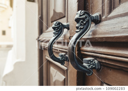Retro vintage door handles close up. Old wooden door with beautiful retro door knobs. 109002283