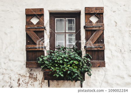 Vintage window with antique wooden shutters decorated with flowers. 109002284
