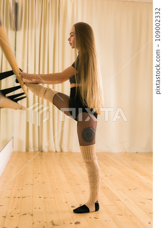 Female ballet dancer practicing at barre in dance studio - dance and ballerina concept 109002332