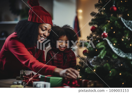 African American mom and daughter decorate a Christmas tree together 109003153