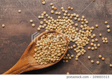 Uncooked lentil legumes in wooden spoon. Top view. 109003313