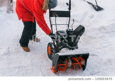 A man clear snow from backyard with snow blower close-up. Winter season and snow blower equipment A man clear snow from backyard with snow blower close-up. Winter season and snow blower equipment 109003670