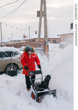 A man clear snow from backyard with snow blower. Winter season and snow blower equipment A man clear snow from backyard with snow blower. Winter season and snow blower equipment 109003672