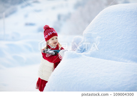 Child brushing off car. Kid with winter snow brush Child brushing off car. Kid with winter snow brush 109004300