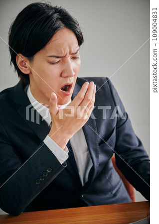 A young male office worker who is sleepy and yawns A young male office worker who is sleepy and yawns 109004831