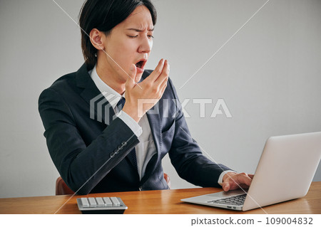 一名昏昏欲睡打哈欠的年輕男性辦公室職員 一名昏昏欲睡打哈欠的年輕男性辦公室職員 109004832