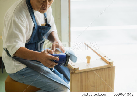 A man sanding a wooden desk A man sanding a wooden desk 109004842