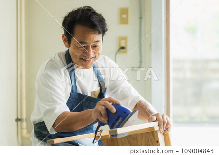 A man sanding a wooden desk 109004843