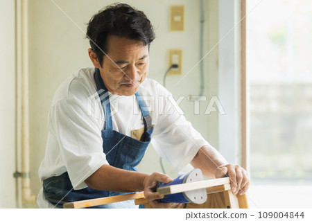 A man sanding a wooden desk 109004844
