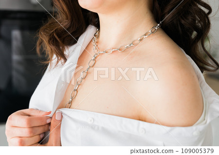 Close-up woman wears massive chain on neck, metal necklace. Modern jewellery concept Close-up woman wears massive chain on neck, metal necklace. Modern jewellery concept 109005379