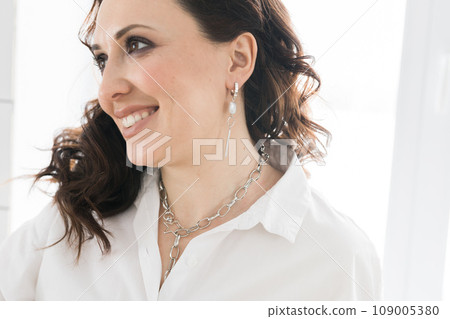 Close-up woman wearing beautiful luxury earrings and necklace. Handmade jewellery and accessories Close-up woman wearing beautiful luxury earrings and necklace. Handmade jewellery and accessories 109005380