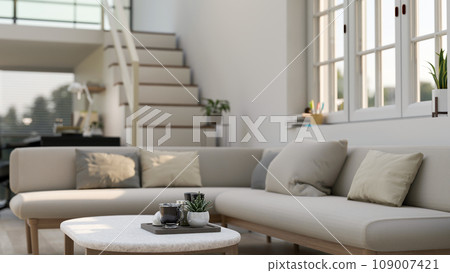 A coffee table in a modern and comfortable living room with a corner couch against the window. A coffee table in a modern and comfortable living room with a corner couch against the window. 109007421