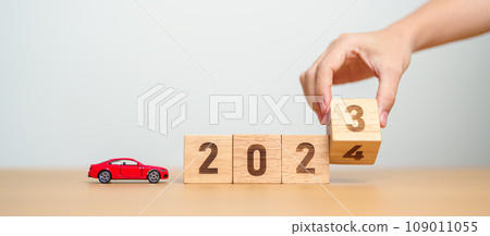 2023 flipping to 2024 year block with car model on table. Automobile Tax, Car Insurance, Financial, vehicle Repair and Maintenance and New Year concept 109011055