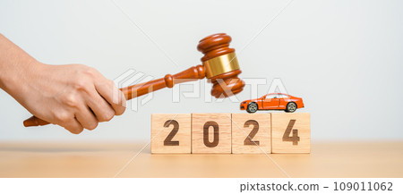 Car Law, Insurance, auto Tax, Auction and Bidding concepts. 2024 year block with crashed small toy car models with Judges gavel on desk in courthouse. 109011062