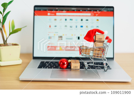 Christmas Online Shopping concept. Boxes with shopping cart on a laptop computer. Sale and discount during Christmas and New Year holiday, ecommerce, shipping delivery, logistics and Cyber Monday 109011900