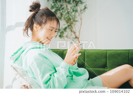 一位穿著家居服使用智慧型手機的女士 109014102