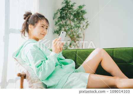 一位穿著家居服使用智慧型手機的女士 109014103
