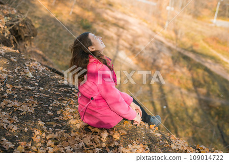 Beautiful happy smiling girl with long hair wearing pink jacket posing in autumn park. Outdoor portrait day light. Autumn mood concept. Generation Z and gen z youth. Copy empty space for text. 109014722