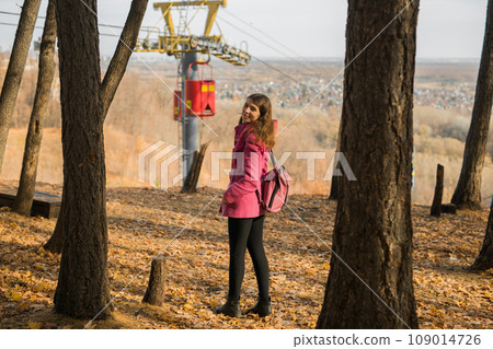 Back view of a girl walking on autumn park in fall season. Generation Z and gen z youth. Copy empty space for text. 109014726