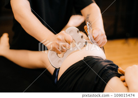 Massage with a special massage paddle, kneading trigger points in the abdomen, close-up. Blade massage. Side view. High quality photo Massage with a special massage paddle, kneading trigger points in the abdomen, close-up. Blade massage. Side view. High quality photo 109015474