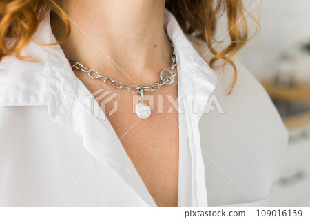 Close-up woman wearing beautiful luxury necklace with pearl pendant. Handmade jewellery and accessory Close-up woman wearing beautiful luxury necklace with pearl pendant. Handmade jewellery and accessory 109016139