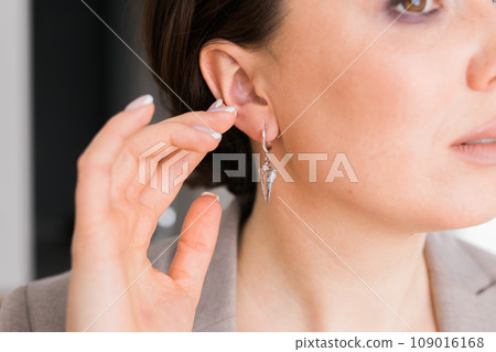 Detail of young woman wearing beautiful luxury earring close-up. Handmade jewellery and accessories 109016168
