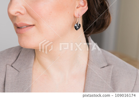 Detail of young woman wearing beautiful luxury earring close-up. Handmade jewellery and accessories Detail of young woman wearing beautiful luxury earring close-up. Handmade jewellery and accessories 109016174