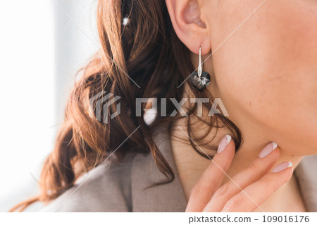 Detail of young woman wearing beautiful luxury earring close-up. Handmade jewellery and accessories Detail of young woman wearing beautiful luxury earring close-up. Handmade jewellery and accessories 109016176