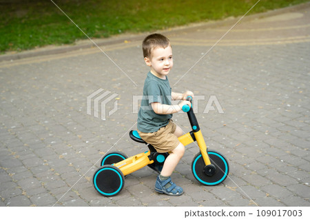 A cute toddler boy of two or three years old rides a bicycle or balance bike in a city park on a sunny summer day. Toddlerhood and childhood concept. Selective focus A cute toddler boy of two or three years old rides a bicycle or balance bike in a city park on a sunny summer day. Toddlerhood and childhood concept. Selective focus 109017003