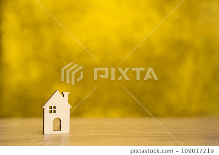 Miniature wooden house on a yellow background. Real estate and affordable housing concept. Mortgage, loan and insurance of apartments. Selling and buying home. Copy space 109017219