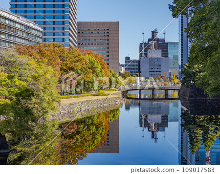 Autumn Tokyo cityscape: Hirakawa Bridge spanning the inner moat of the Edo Castle ruins, autumn leaves and buildings reflected on the water surface Autumn Tokyo cityscape: Hirakawa Bridge spanning the inner moat of the Edo Castle ruins, autumn leaves and buildings reflected on the water surface 109017583