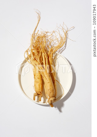 Background of ginseng for healthcare concept. Top view of ginseng roots on white round ceramic dish on white background. Scene for advertising herbal ingredient with ginseng 109017943