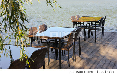 Recreation area in the city park. Outdoor tables and benches by the lake for relaxing and eating Recreation area in the city park. Outdoor tables and benches by the lake for relaxing and eating 109018344