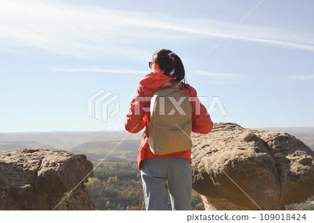 Active young woman with backpack hiking in the mountains enjoying panoramic views. 109018424