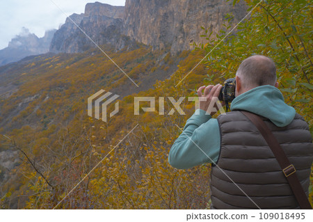 a tourist takes pictures of a beautiful autumn mountain landscape using a camera 109018495