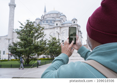 A male tourist takes a photo of the Fatih Mosque in Istanbul, Turkey as a keepsake. A male tourist takes a photo of the Fatih Mosque in Istanbul, Turkey as a keepsake. 109018506