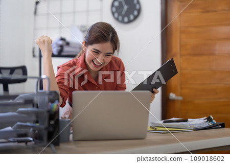 Happy excited business woman in office working with computer make winner gesture. excited success business asian woman triumph in office Happy excited business woman in office working with computer make winner gesture. excited success business asian woman triumph in office 109018602