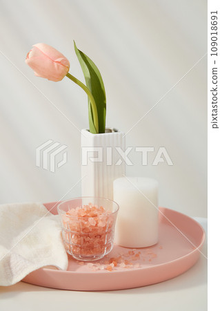Pink himalayan salt contained inside glass cup, displayed with scented candle and a flower pot on pink tray. The coarse texture of Himalayan salt can do wonders for our bodies as a scrub Pink himalayan salt contained inside glass cup, displayed with scented candle and a flower pot on pink tray. The coarse texture of Himalayan salt can do wonders for our bodies as a scrub 109018691