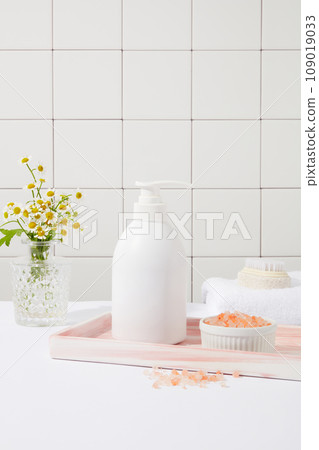 A marble tray feature a pump bottle and a bowl of pink himalayan salt. Pink Himalayan salt is less processed than table salt. Branding mockup design 109019033