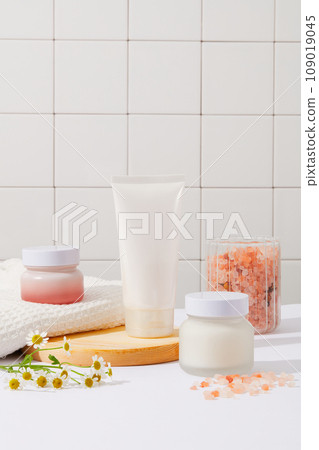 A set of cosmetic packages displayed in the bathroom with a jar containing pink himalayan salt. Pink himalayan salt is not technically from the Himalayas. Mockup design 109019045