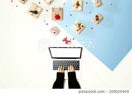 Person using a laptop computer with Christmas gift boxes Person using a laptop computer with Christmas gift boxes 109020409