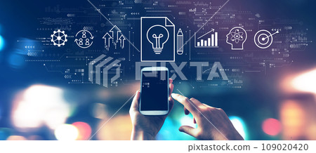 Idea of success theme with a smartphone in city lights at night Idea of success theme with a smartphone in city lights at night 109020420