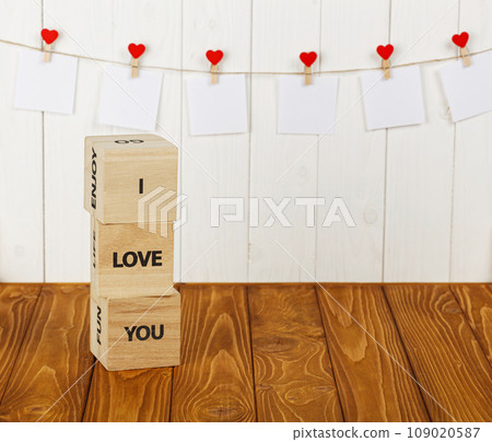 white pieces of paper on clothespins with a heart on a wooden background, a wooden inscription I love you 109020587