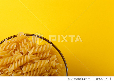 Different types and shapes of dry italian pasta on a yellow background Different types and shapes of dry italian pasta on a yellow background 109020621