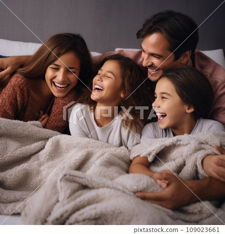 A mother, father, and their two children cuddled up on a fluffy blanket 109023661