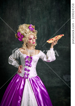Beautiful woman with bright make up looking at seductive huge American hot dog with souses against vintage background. Beautiful woman with bright make up looking at seductive huge American hot dog with souses against vintage background. 109024158
