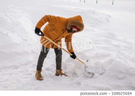 Man removing snow and ice from the sidewalk in front of house. Winter season 109025084